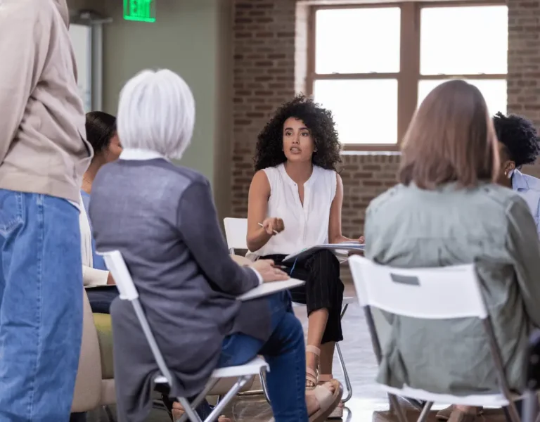 Woman speaking at a homeowners association meeting seated in a circle of chairs in Columbus, OH